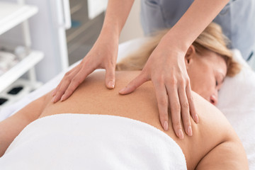 Obraz na płótnie Canvas Close-up of unrecognizable therapist giving relaxing back massage to exhausted woman in spa salon