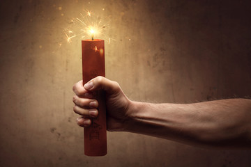 Risk concept - Hand holding a burning stick of dynamite