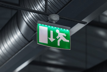 Fototapeta na wymiar Emergency exit sign with stainless steel ventilation pipes in background