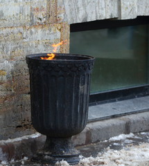 Obraz premium Street black metal urn with burning garbage