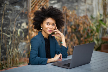 smiling african american businesswoman sitting with laptop computer - Powered by Adobe