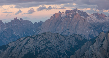 Mountain landscape in the European Dolomite Alps underneath the Three Peaks with alpenglow during sunset, coloured clouds in the sky, South Tyrol Italy.