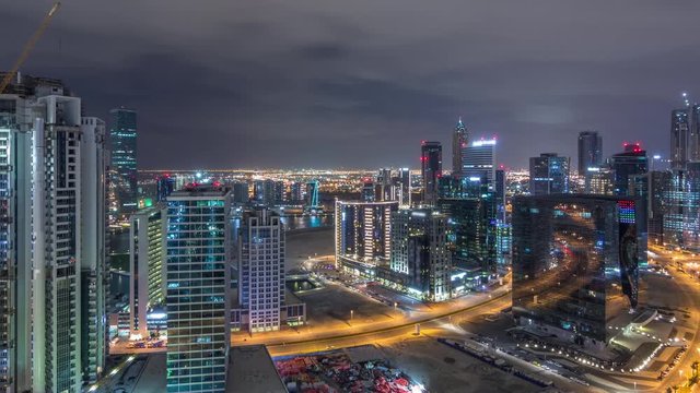 Aerial view of illuminated buildings timelapse during all night and high traffic on roads near canal. Night life in Business Bay, Dubai, United Arab Emirates