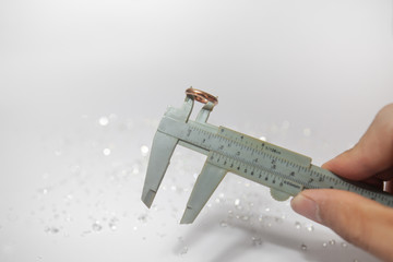 Hand holding a pinchbeck ring with vernier caliper. Worker measures the diameter of ring on a...