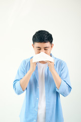 Young asian man sneezing after get allergy or flu virus and using tissue paper for swipe on nose at...