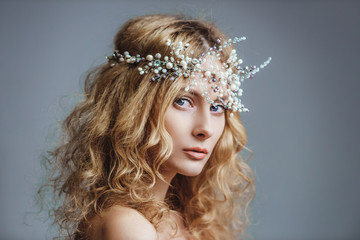 Young blue-eyed girl in with hair jewelry. Young woman with a hoop with stones and pearls. The concept of a wedding hairstyle and jewelry