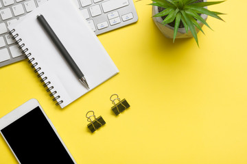 Yellow desk office with laptop, smartphone and other work supplies with cup of coffee. Top view...