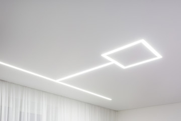looking up on suspended ceiling with halogen spots lamps and drywall construction in empty room in...