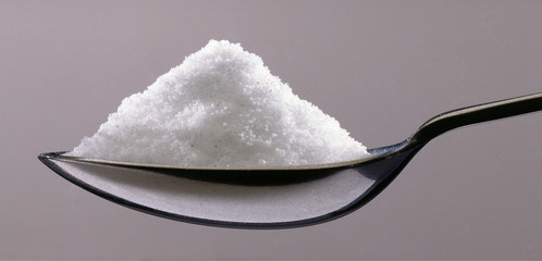Salt portion on teaspoon macro photography.