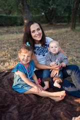 A young mom with young, adorable kids wasteland in the park. Autumn picnic