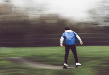 Active man skateboarding along path in park
