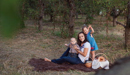 Family portrait of a young mom with babies. Beautiful mother with children in autumn garden