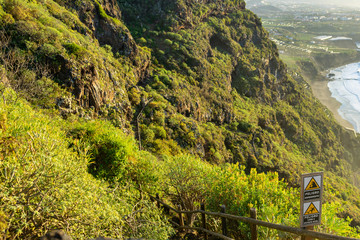 Viewpoint in Santa Ursula, Tenerife. You can see a cliff and a black sand beach. You also see a landslide hazard sign and a slippery floor sign. © AventurasxCanarias
