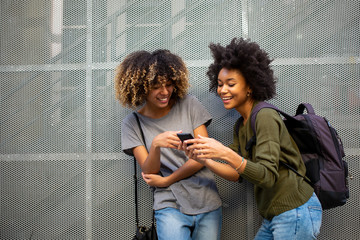 happy young african american women friends with mobile phone and bags