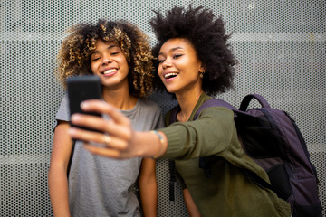 two young african american friends taking selfie with mobile phone