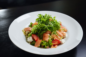 Fresh salad with raw salmon on plate.