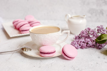 A Cup of morning coffee, a bowl of lilac, macaroni, on a light background. Postcard good morning