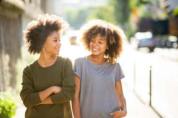 two black female friends walking and smiling in city