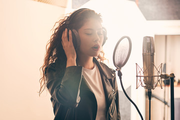 Pretty female singer recording in music studio - Powered by Adobe