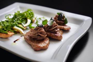 Beef steaks and toasts with avocado and rucola.