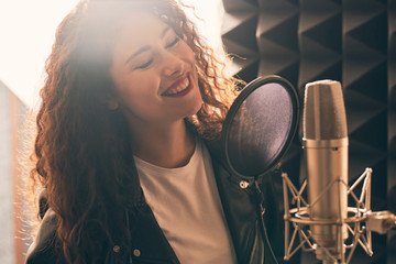 Pretty female singer recording in music studio