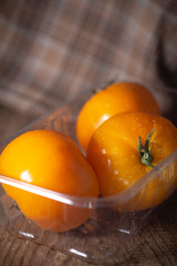 Fresh organic yellow tomatoes on wooden background