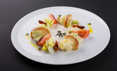 Ceasar salad with bacon served on a white plate