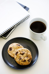 cup of hot black coffee on white table background with notebook and stationery.  Work from home concept.