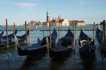 Góndolas atracadas en la laguna de Venecia con la basílica Di San Giorgo Maggiore al fondo.
