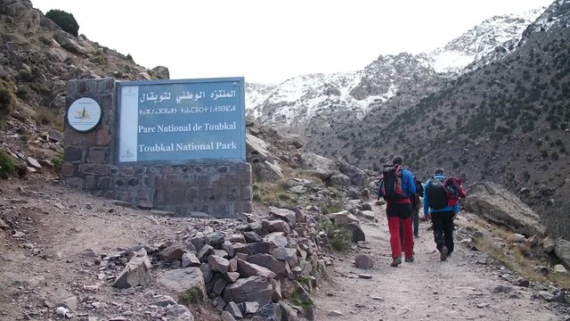 Guys entering Toubkal National Park while Toubkal trek with snowy mountains in the back.
High angle, traveling movement, slow motion, HD.