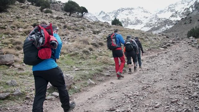 Guys while Toubkal trek with snowy mountains in the back.
High angle, traveling movement, slow motion, HD.