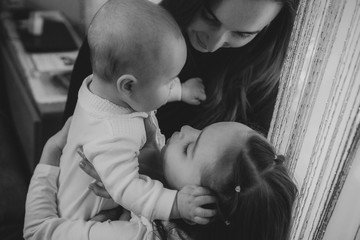 happy mother holds a little son and next to her is a daughter who wants to kiss him