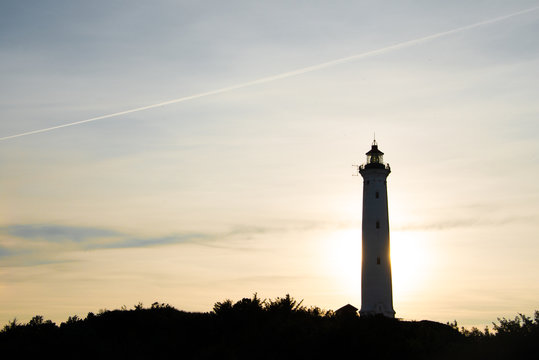 Silhouette aus der Ferne - ein Leuchtturm an der Nordseek&uuml;ste im Gegenlicht des Abends