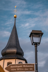 Fototapeta na wymiar Church tower and Lamp with a street sign