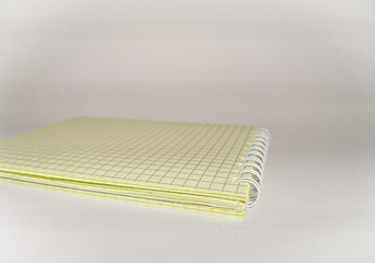 Close-up of a notepad with yellow squared sheets and a white spring. Macro shooting. Image with selective focus.