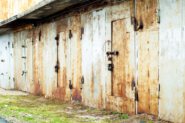 Iron garages in a row. Rusty, old doors and gates of garages.