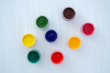 Gouache paints in jars. Bright color. Red, pink, yellow, orange, blue and green colors in small jars. The view from the top. Flat lay