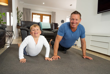 COVID-19 Outrbreak. Father and son exercising together at home during coronavirus quarantine
