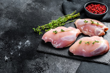 Raw boneless chicken thighs fillet. Black background. Top view. Copy space