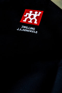 Illustrative editorial of Zwilling J.A. Henckels kitchen knife and black apron with logo with copyspace