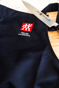 Illustrative editorial of Zwilling J.A. Henckels kitchen knife and black apron with logo with copyspace
