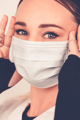 Jeune femme avec un masque chirurgical pour se protéger des virus sur fond uni blanc