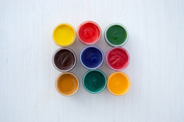 Gouache paints in jars. Bright color. Red, pink, yellow, orange, blue and green colors in small...