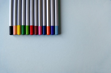 Many color pencils lies on light grey background. Art concept