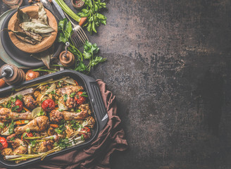 Rustic food background with oven roasted chicken and vegetables in black grill frying pan on rustic background . Top view