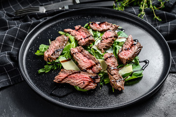 Steak salad with spinach, arugula and sliced beef marbled steak. Black background. Top view