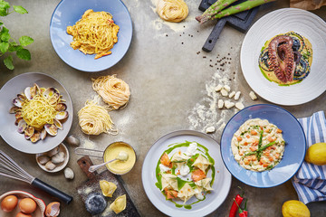 seafood dishes with homemade pasta and other ingredients on stone table background, top view, copy space, empty space 