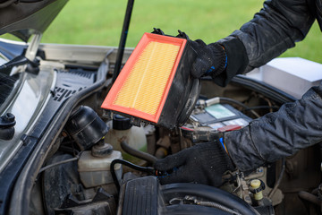 Obraz premium Man replaces a dirty air filter for a new one in a car. car service