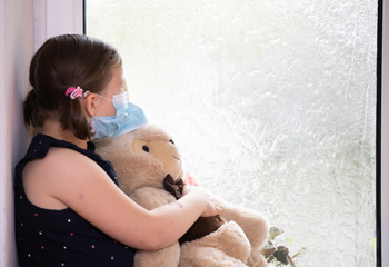 Little girl looking out the window. Coronavirus pandemic, stay ay home concept.