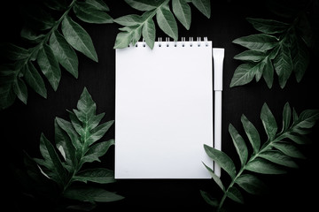 White notebook on tropical leaves background